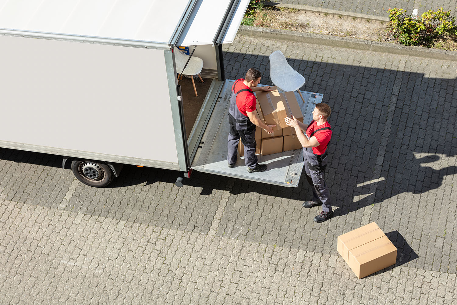 Male Movers Unloading The Cardboard Boxes Form Truck